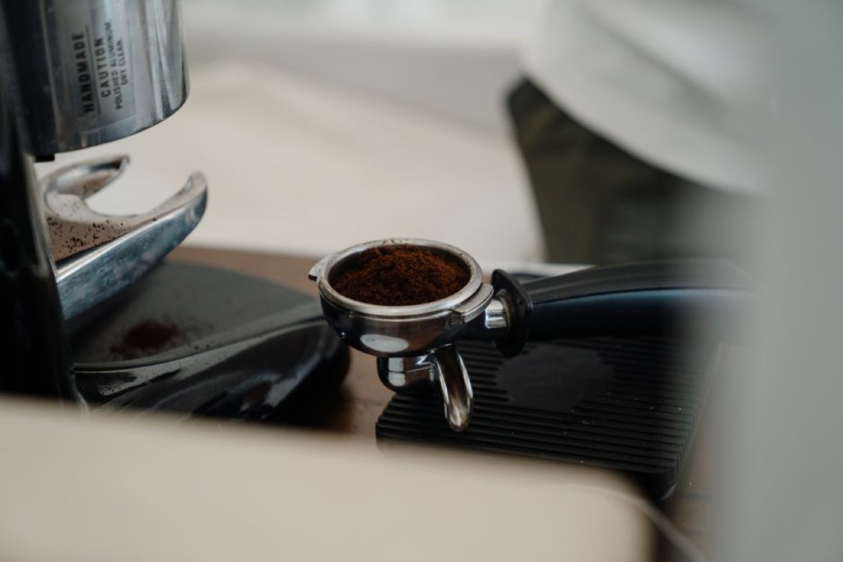 Freshly dosed portafilter basket with ground espresso coffee ready for tamping