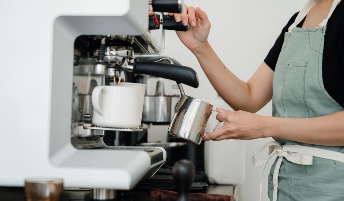 Home barista preparing espresso with grinder and machine on kitchen counter