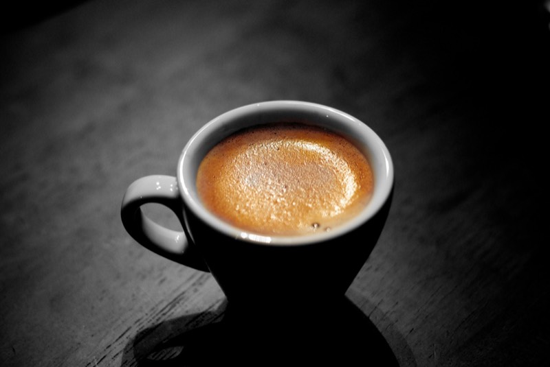 Perfectly balanced espresso shot with thick golden crema in a white demitasse cup