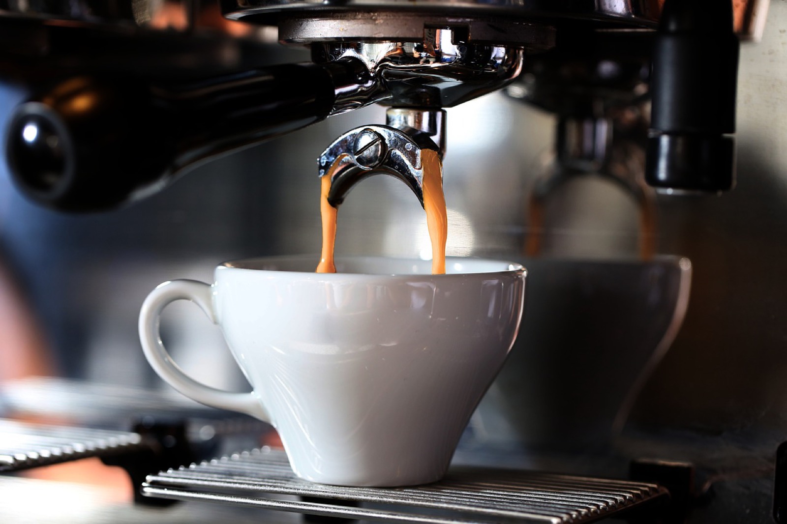 Espresso shot extracting into a cup, showing crema color used to judge sour under-extraction